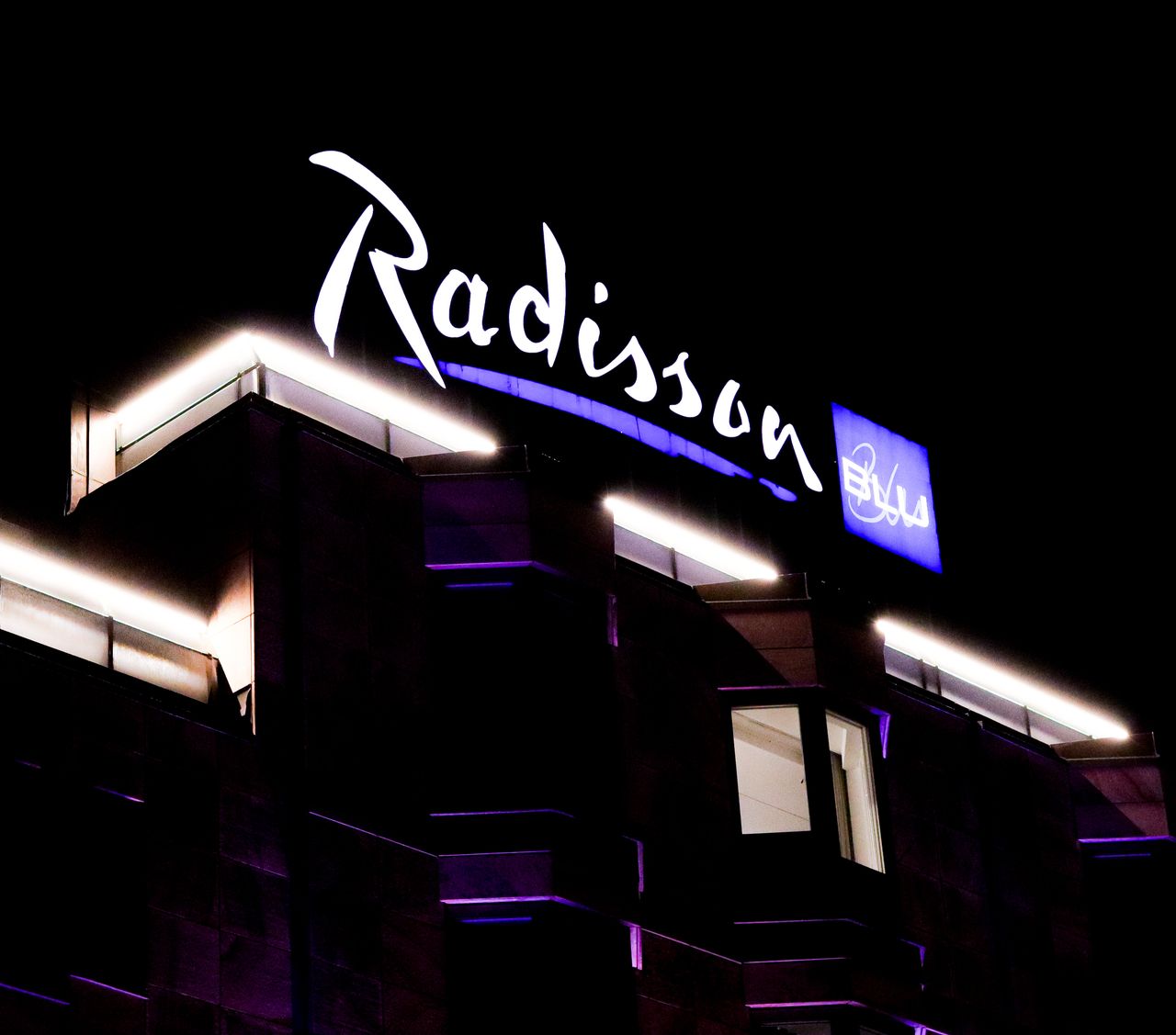 Portfolio Illuminated Radisson Blu hotel building with neon signage captured at night.