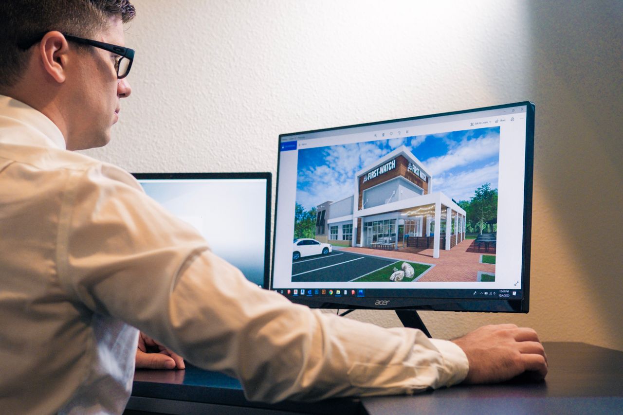 Services Architect evaluating a building design on a computer screen in an office setting.