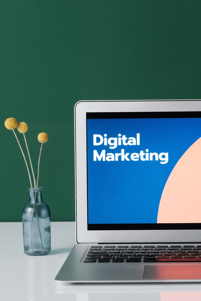 Portfolio A laptop displaying 'Digital Marketing' with a minimalist floral decor in a glass vase.
